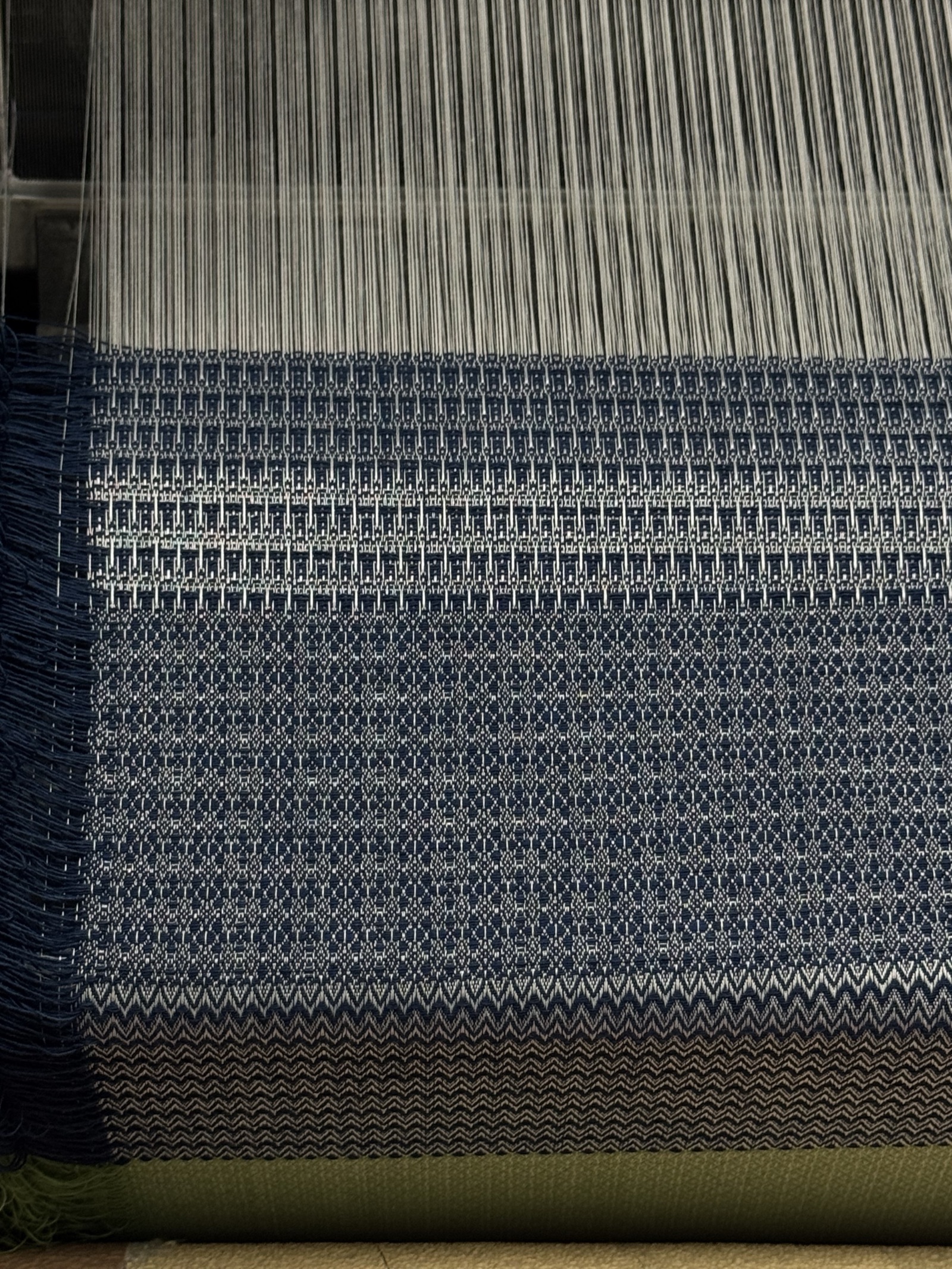 Navy and white dobby cloth being woven on the loom.