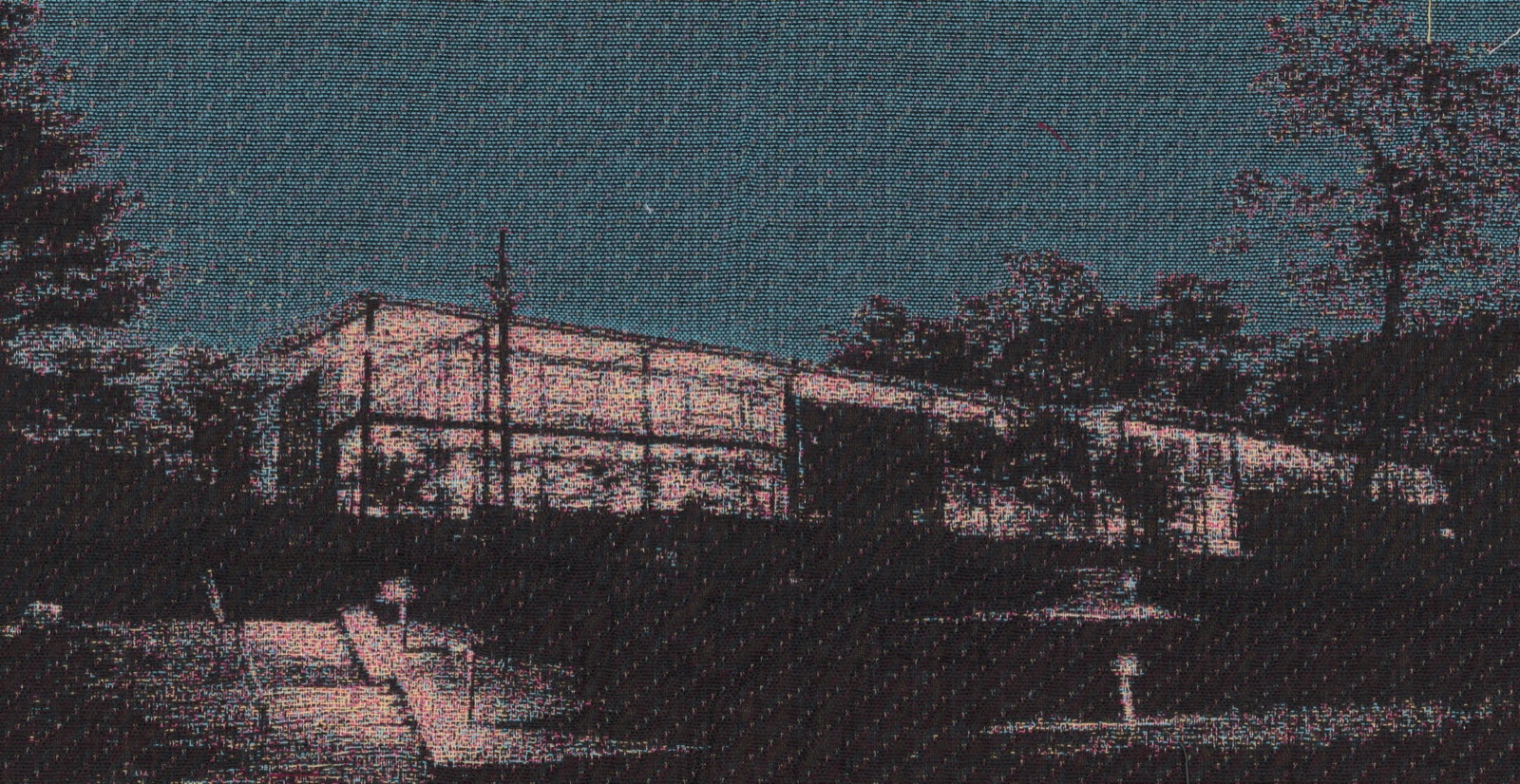 Jacquard-woven cloth — a building lit at dusk among dark trees, the image carried entirely in the interlacing.